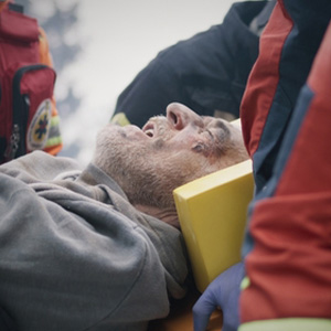 Injured man being carried on a stretcher by paramedics after an emergency accident