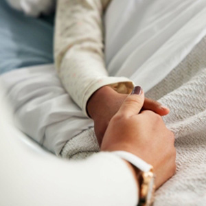 Doctor holding a patient’s hand in a moment of care and reassurance.