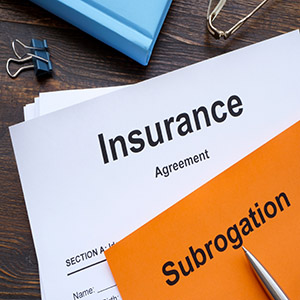 Insurance Agreement document with a bright orange Subrogation tag and a pen.